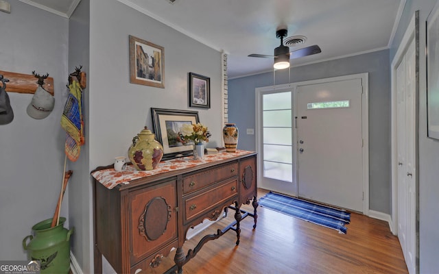 entrance foyer featuring ornamental molding, light wood-type flooring, and ceiling fan