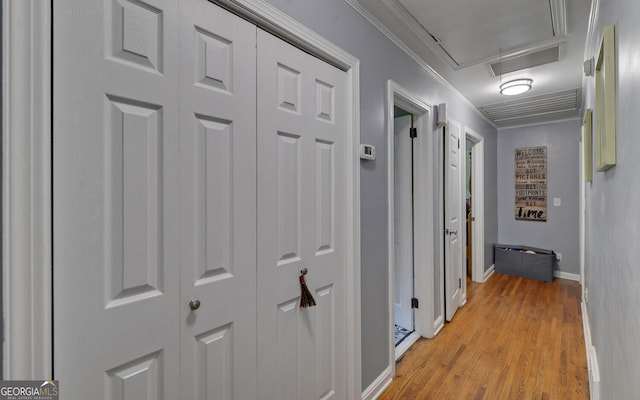 corridor with ornamental molding and light hardwood / wood-style floors