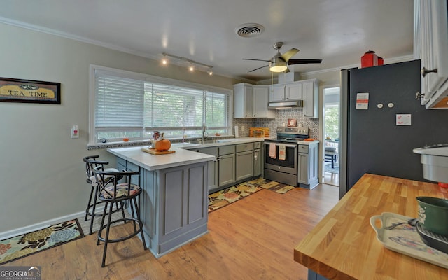 kitchen featuring light wood-type flooring, crown molding, fridge, and stainless steel range with electric cooktop