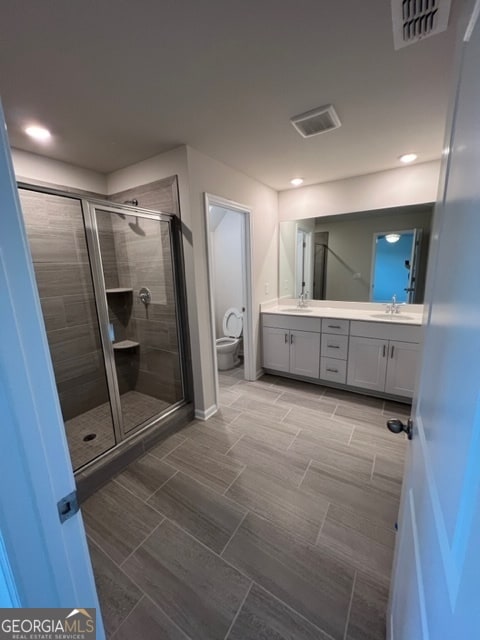 bathroom featuring walk in shower, vanity, and toilet