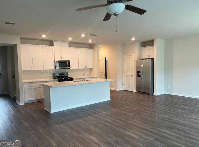 kitchen featuring appliances with stainless steel finishes, a kitchen island with sink, dark hardwood / wood-style floors, and white cabinets