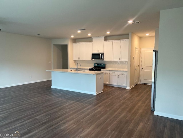 kitchen featuring sink, a center island with sink, white cabinetry, dark hardwood / wood-style floors, and black stove