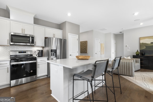 kitchen featuring a kitchen island, appliances with stainless steel finishes, dark hardwood / wood-style flooring, and white cabinetry