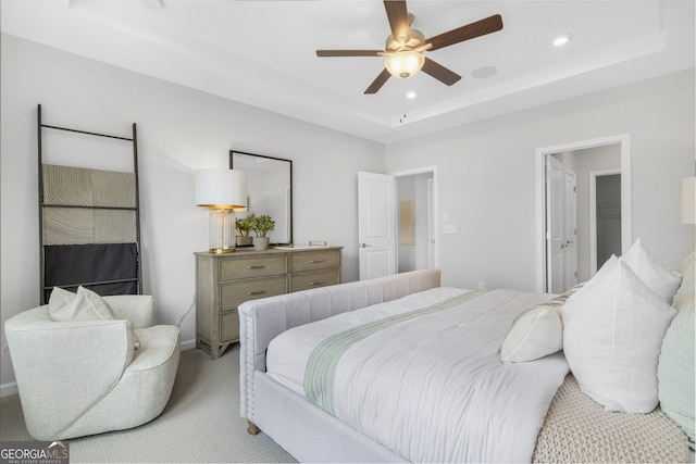 carpeted bedroom featuring ceiling fan and a raised ceiling