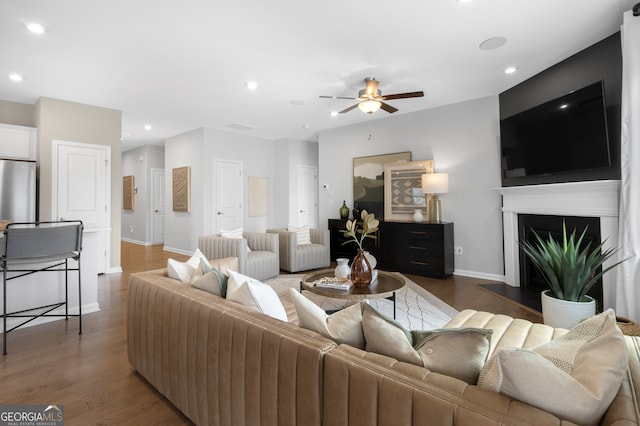 living room featuring ceiling fan and dark hardwood / wood-style floors