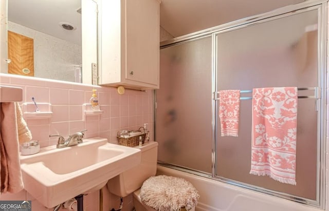 full bathroom with toilet, combined bath / shower with glass door, and tile walls