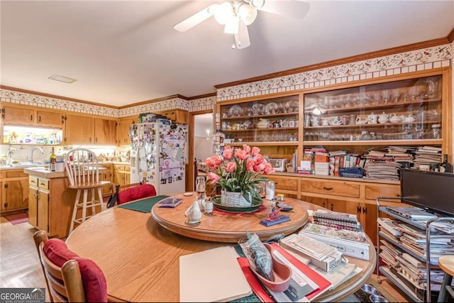 dining space with ornamental molding, sink, and ceiling fan