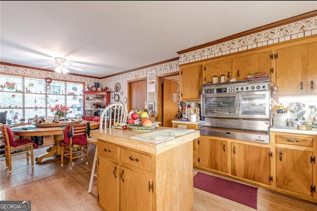 kitchen featuring crown molding, stainless steel oven, light hardwood / wood-style flooring, and a kitchen island