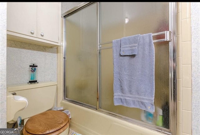 bathroom featuring enclosed tub / shower combo and toilet