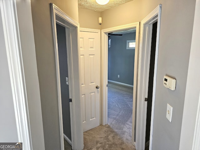 corridor with carpet floors and a textured ceiling