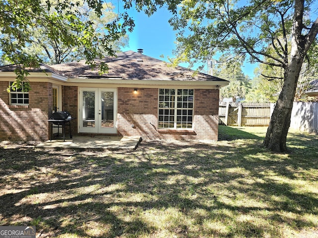 rear view of house featuring french doors and a lawn