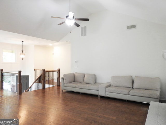 living room with vaulted ceiling, ceiling fan with notable chandelier, and dark wood-type flooring