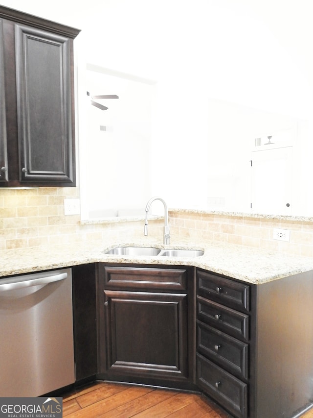 kitchen with backsplash, light stone countertops, dishwasher, hardwood / wood-style flooring, and sink