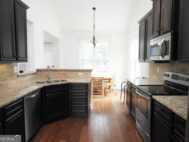 kitchen with appliances with stainless steel finishes, backsplash, lofted ceiling, and dark hardwood / wood-style floors