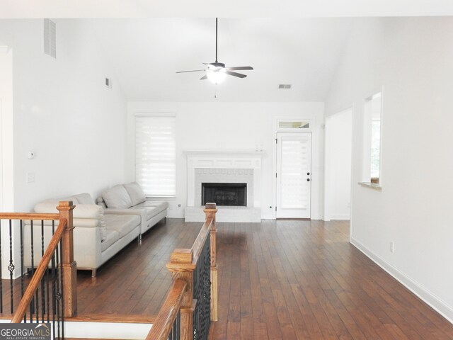 unfurnished living room featuring vaulted ceiling, dark hardwood / wood-style flooring, ceiling fan, and a brick fireplace