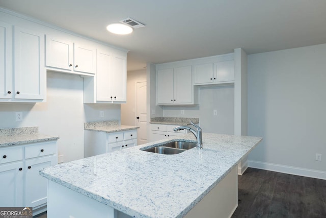 kitchen with an island with sink, white cabinets, and dark wood-type flooring