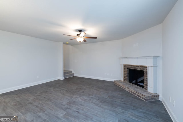 unfurnished living room with ceiling fan, a brick fireplace, and dark hardwood / wood-style flooring