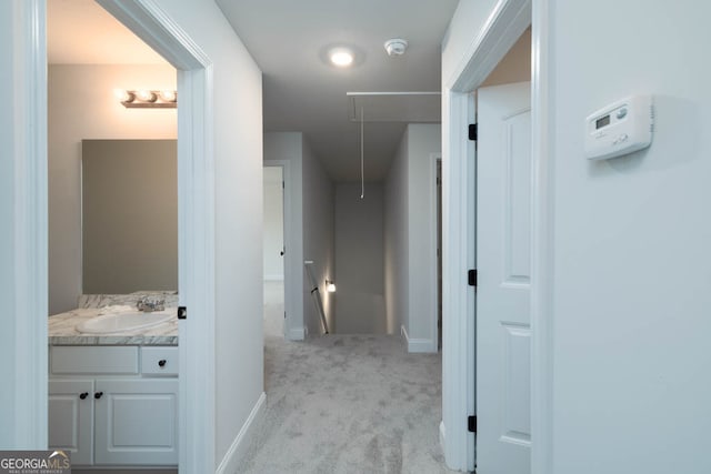 hall with light colored carpet and sink