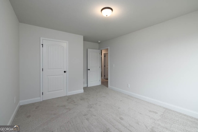 unfurnished bedroom featuring light colored carpet and a closet