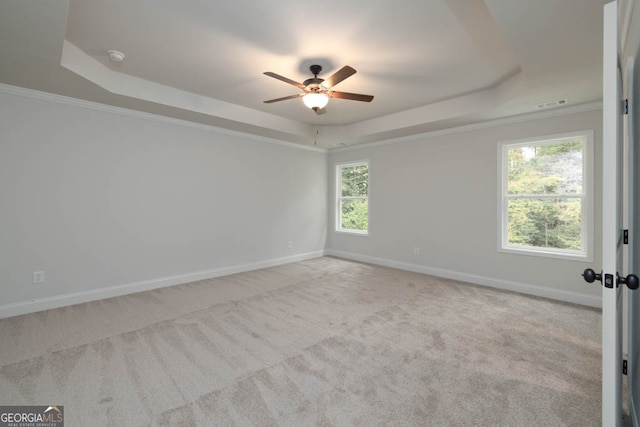 spare room featuring ceiling fan, light colored carpet, a tray ceiling, and crown molding