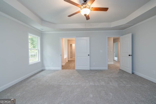 unfurnished bedroom featuring ceiling fan, light colored carpet, a tray ceiling, and crown molding