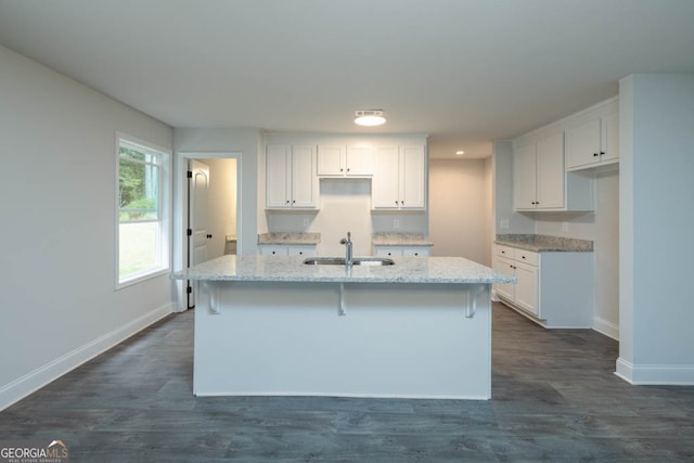 kitchen with an island with sink, dark hardwood / wood-style floors, sink, and white cabinetry