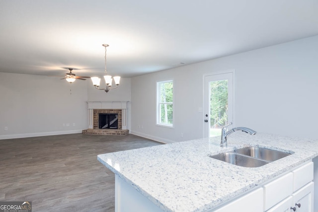 kitchen with white cabinets, a brick fireplace, decorative light fixtures, dark hardwood / wood-style flooring, and light stone countertops