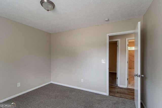 unfurnished room with dark carpet and a textured ceiling