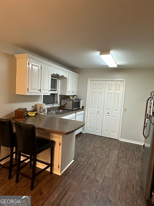 kitchen featuring white cabinets, appliances with stainless steel finishes, kitchen peninsula, and a breakfast bar