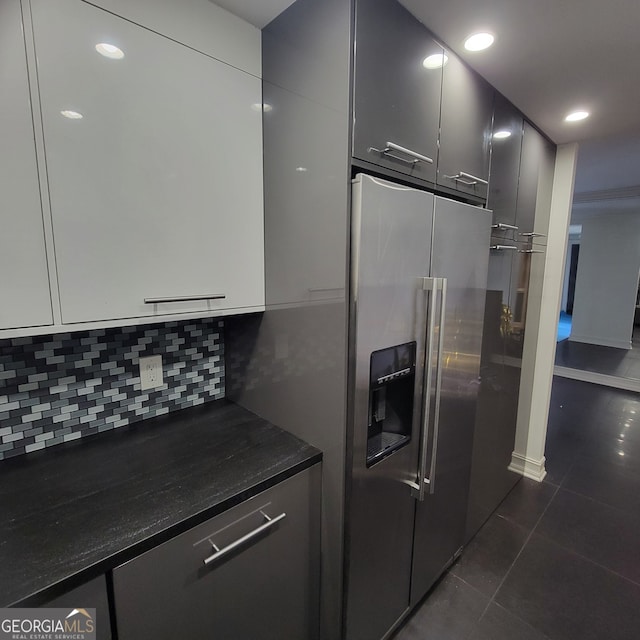 kitchen with dark tile patterned flooring, high quality fridge, and backsplash