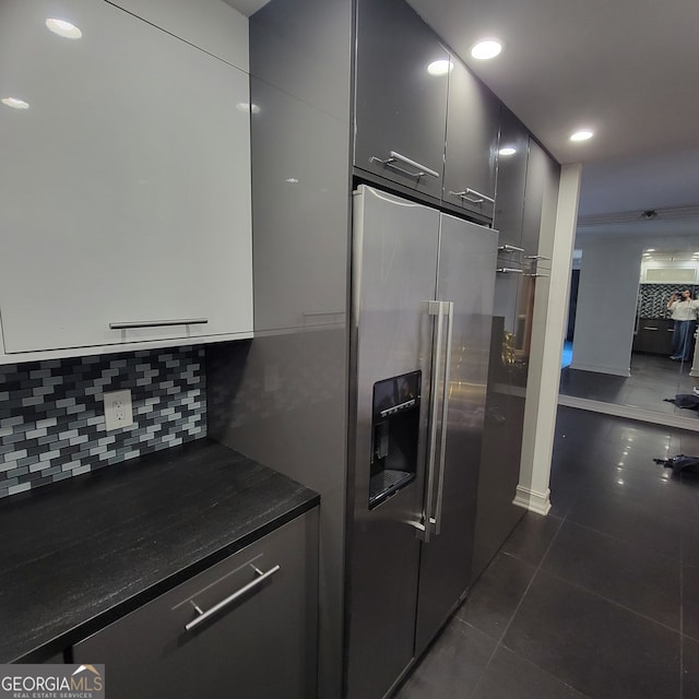 kitchen featuring tasteful backsplash, dark tile patterned floors, and stainless steel refrigerator with ice dispenser