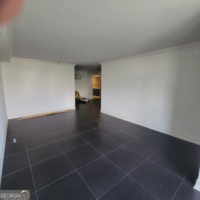 empty room with crown molding and dark tile patterned floors