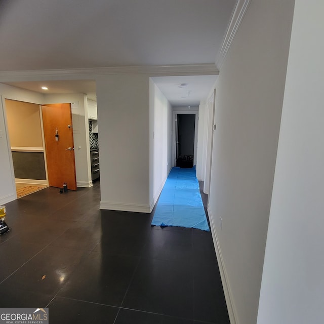 hallway featuring dark tile patterned flooring and ornamental molding