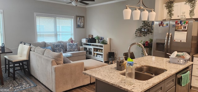 kitchen with light stone countertops, appliances with stainless steel finishes, a kitchen island with sink, and dark hardwood / wood-style floors