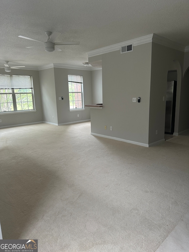 empty room with ceiling fan, light colored carpet, a textured ceiling, and ornamental molding