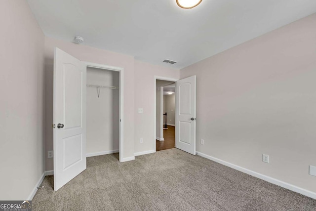 unfurnished bedroom featuring light carpet and a closet