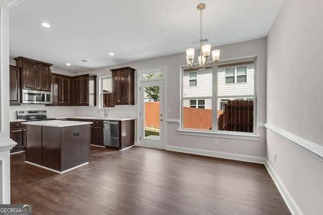 kitchen with appliances with stainless steel finishes, dark wood-type flooring, dark brown cabinets, decorative light fixtures, and a chandelier