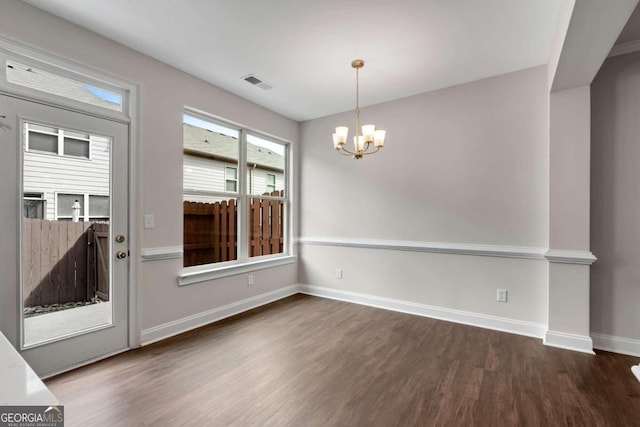 empty room featuring an inviting chandelier and dark hardwood / wood-style floors