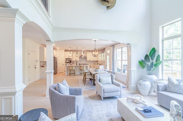 living room with light hardwood / wood-style flooring, a high ceiling, and ornate columns