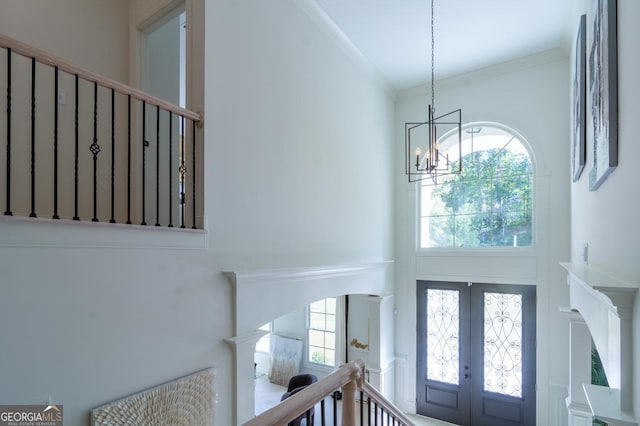 foyer with a chandelier, french doors, and crown molding