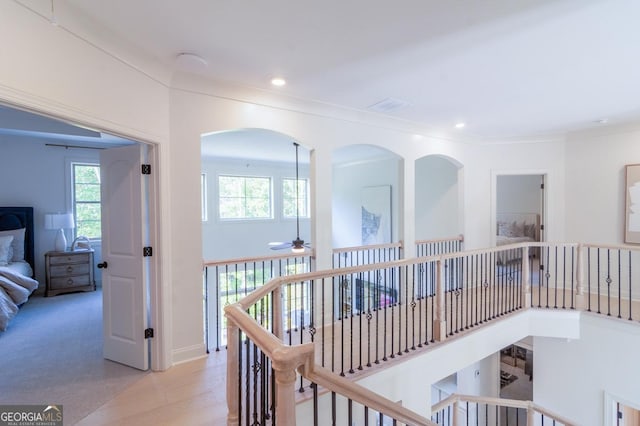 hallway with ornamental molding and light hardwood / wood-style floors