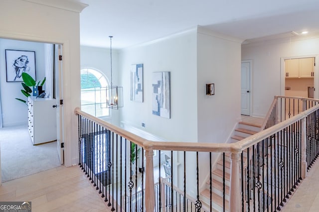 hallway featuring light wood-type flooring, crown molding, and a chandelier