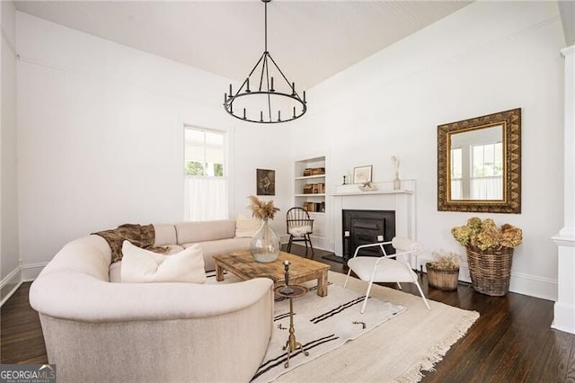 living room with an inviting chandelier, dark hardwood / wood-style flooring, and built in shelves