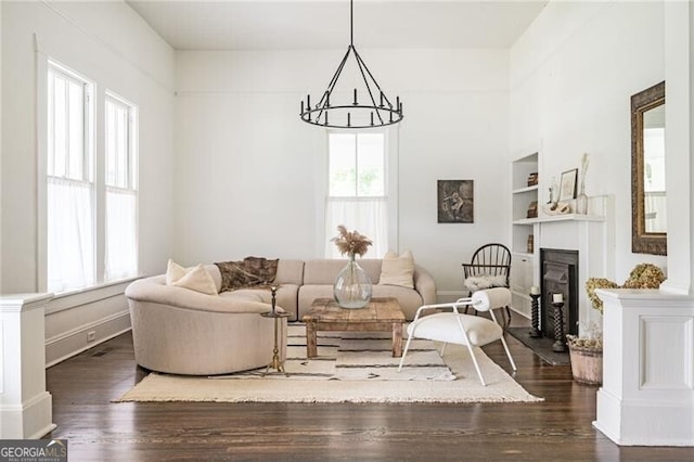 living room with built in shelves, dark hardwood / wood-style floors, and a notable chandelier