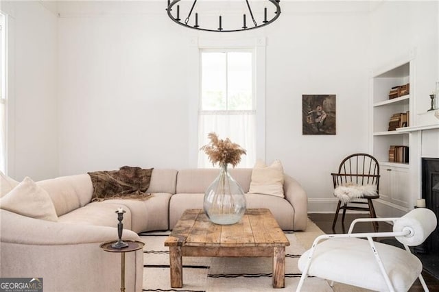 living room featuring wood-type flooring, a chandelier, and built in shelves