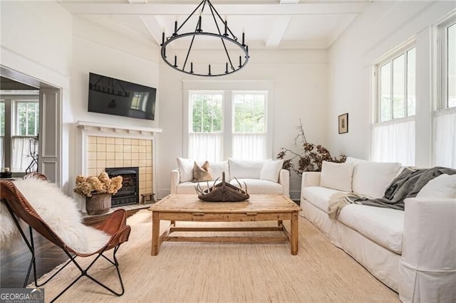 living room with beamed ceiling, a fireplace, an inviting chandelier, and hardwood / wood-style flooring