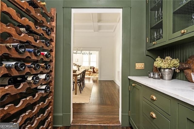 wine area with dark hardwood / wood-style floors, coffered ceiling, and beam ceiling