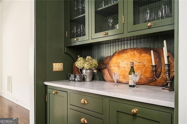 bar featuring wood-type flooring and green cabinets