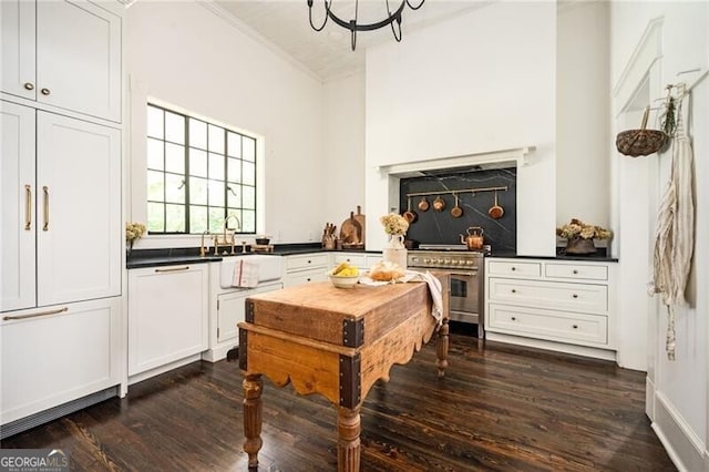 kitchen featuring dark hardwood / wood-style floors, stainless steel stove, sink, white cabinets, and a chandelier