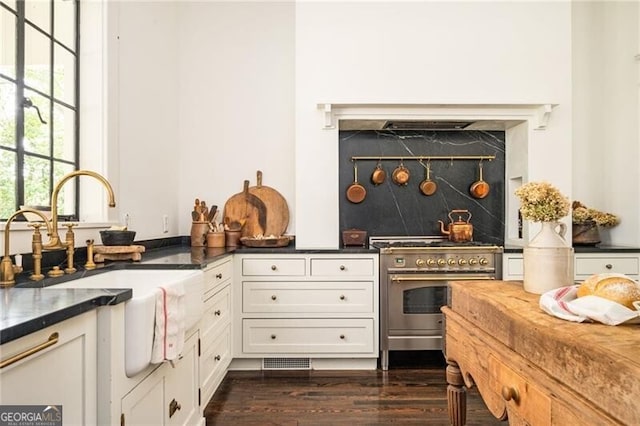 kitchen featuring dark hardwood / wood-style flooring, high end stainless steel range, sink, and white cabinets